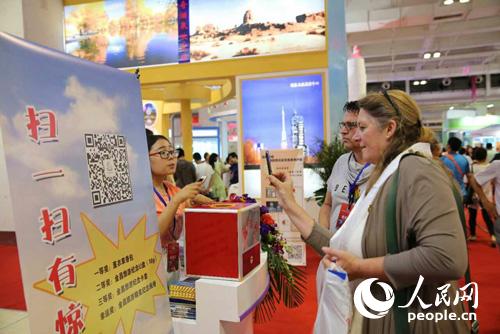 金昌旅游商品驚艷亮相絲綢之路旅游產(chǎn)品展(圖4) 外商參與金昌現(xiàn)場(chǎng)掃碼活動(dòng)